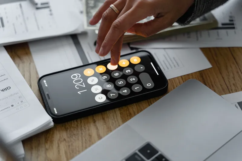 Hands using a calculator beside paperwork